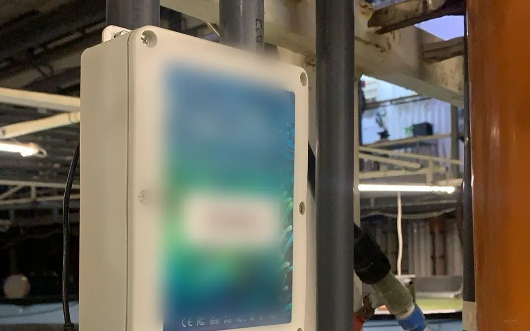 An Omni controller mounted on pipework inside an indoor recirculating aquaculture facility, with tanks and process piping behind